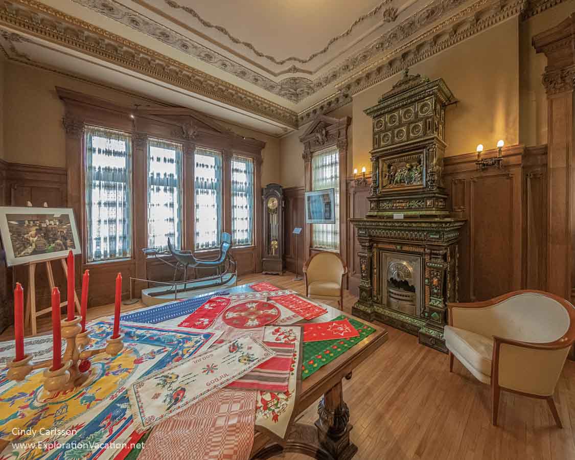 room with big windows, tile stove, and table with Christmas decorations