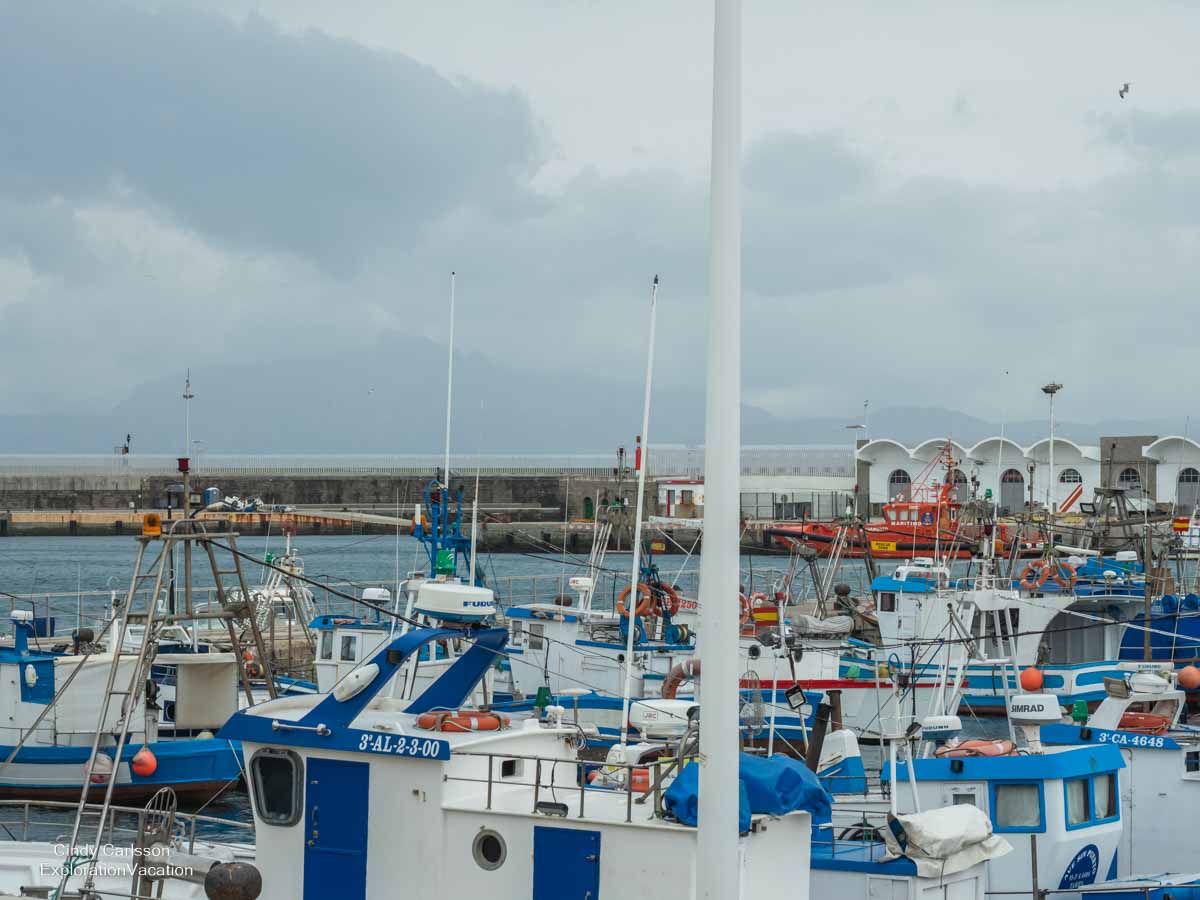 photo of boats in harbor in Tarifa Spain with Morocco barely visible in the distance © Cindy Carlsson at ExplorationVacation