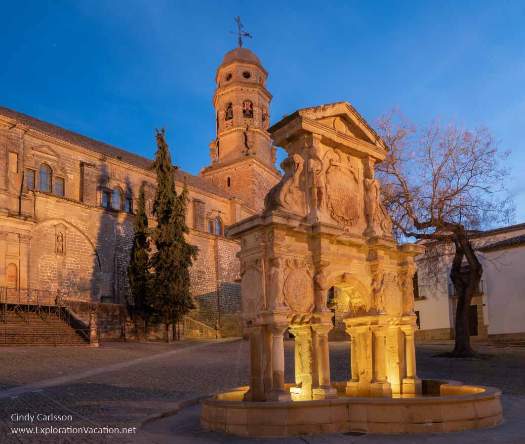 An ancient Roman well and cathedral with golden lighting at sunset in Baeza, Spain.