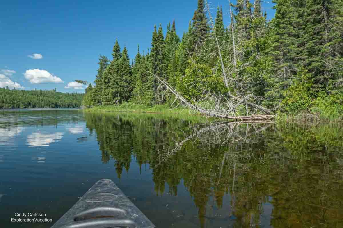 photo of the front of a canoe and lakeshore while canoeing on Loon Lake on Minnesota's Gunflint Trail © Cindy Carlsson at ExplorationVacation