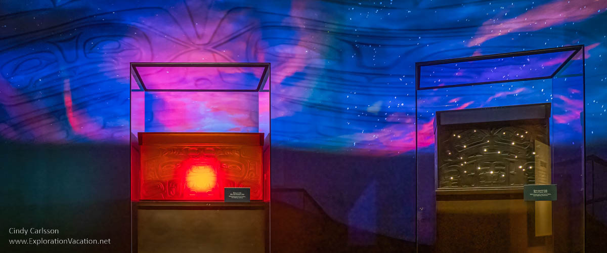 phot of red and blue glass boxes with the sun and stars glowing inside with projections above created by Tlingit artist Preston Singletary for "Raven and the Box of Daylight" at the National Museum of the American Indian Washington DC © Cindy Carlsson at ExplorationVacation.net