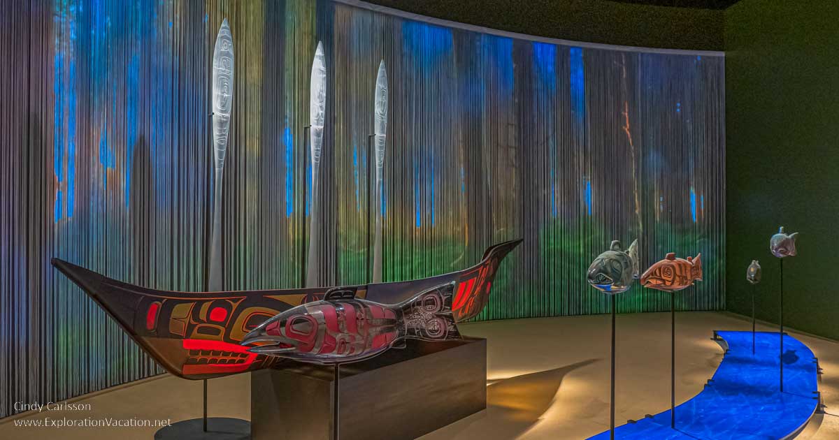 photo of a scene with a canoe, salmon, and raised paddles (all made of glass), by Tlingit artist Preston Singletary for "Raven and the Box of Daylight" at the National Museum of the American Indian Washington DC © Cindy Carlsson at ExplorationVacation.net