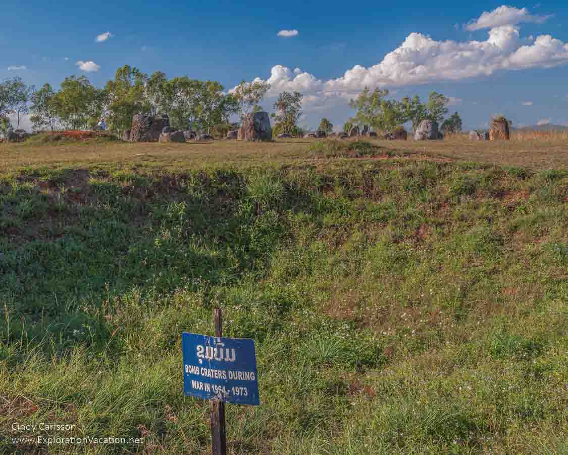 photo of bomb crater with stone jars in the background at Site 1 at the Plain of Jars UNESCO World Heritage Site Laos &copy; Cindy Carlsson at ExplorationVacation.net 