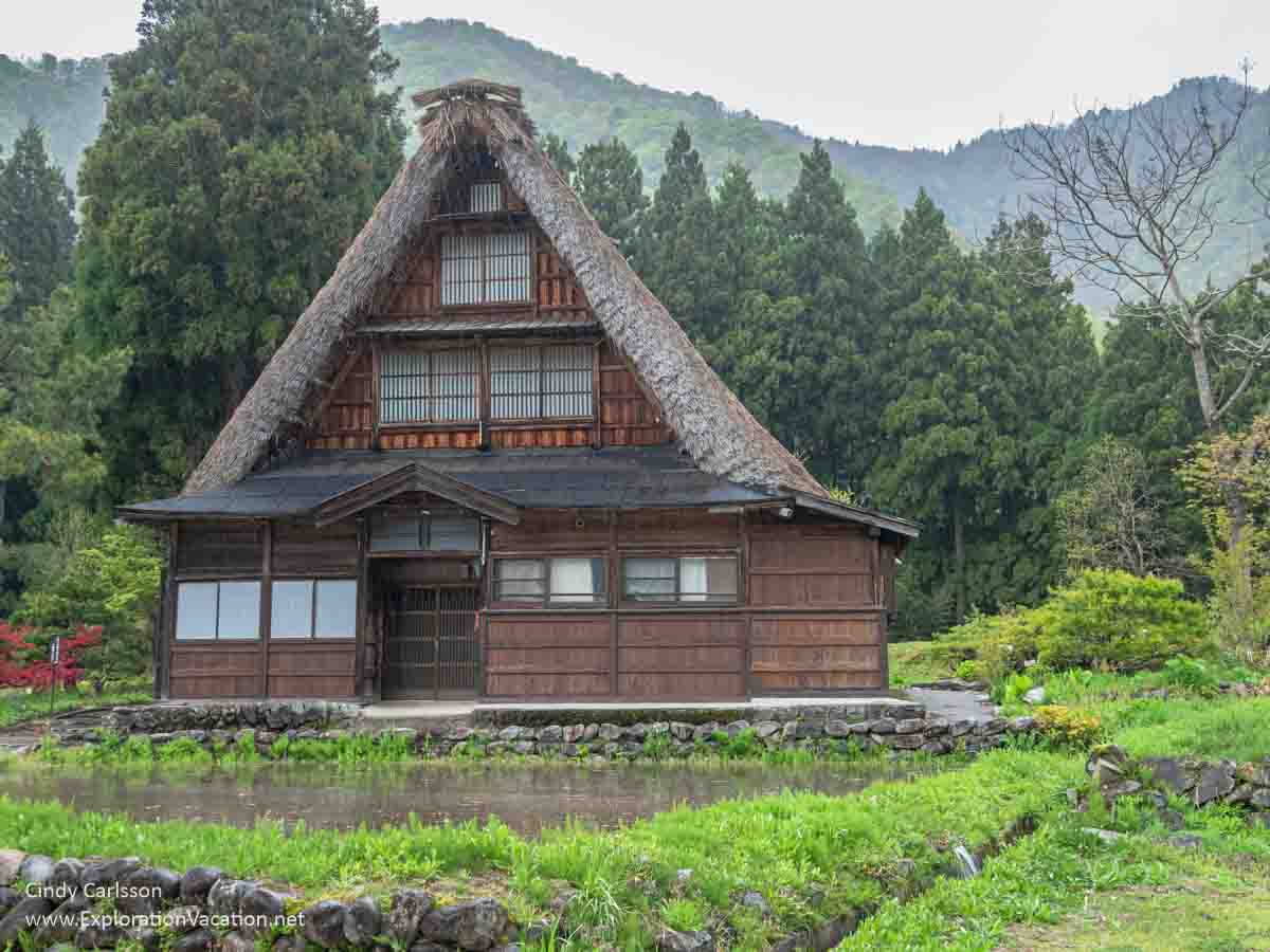 Photo of a wood house with a steeply pitched thatch roof with a flooded field in front and mountains in the background &copy; Cindy Carlsson at ExplorationVacation.net.