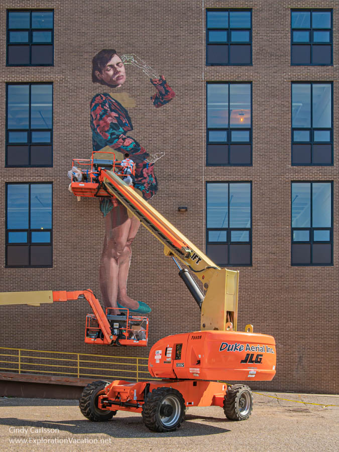Photo of Argentinean artist Mariela Ajras painting “Motherhood and Migration” during the 2019 Chroma Zone Mural and Art Festival in St Paul, Minnesota © Cindy Carlsson at ExplorationVacation.net