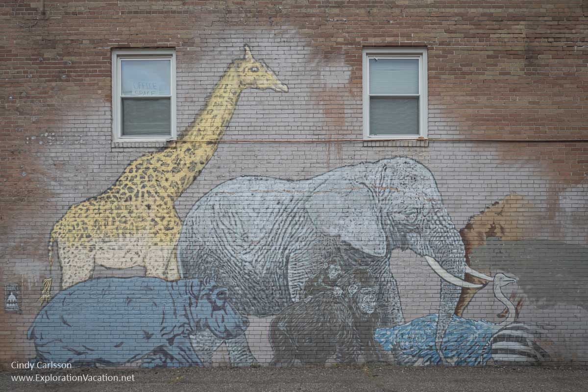 Photo of a faded mural with a giraffe, elephant, hippo and other African wildlife crated in 2012 by Broken Crow as part of “The Bigger Picture Project” along University Avenue in St Paul Minnesota. Photo © Cindy Carlsson at ExplorationVacation.net