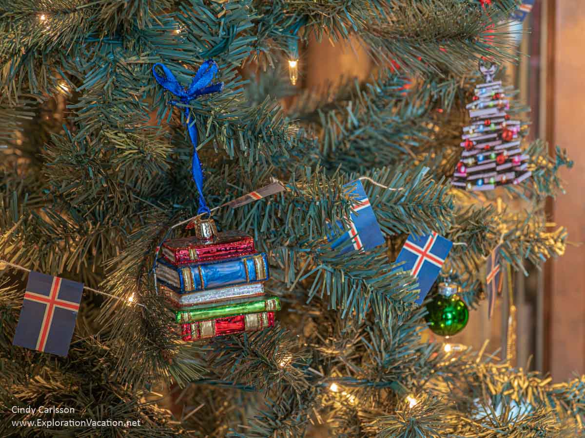 A glass Christmas ornament depicting books on a tree strung with Icelandic flags at the American Swedish Institute (ASI) Christmas display.