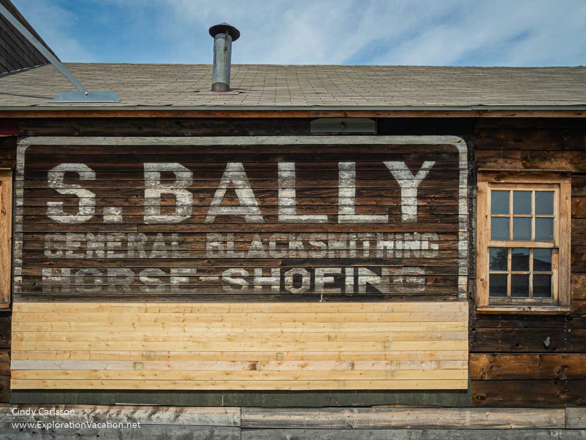 A sign painted on an old building with the name of the Bally Blacksmith Shop.