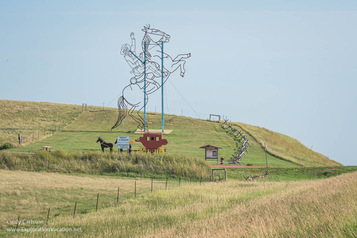 A hillside with an enormous metal outline of Theodore Roosevelt on horseback and a much smaller stagecoach by Gary Greff called Teddy Rides Again.