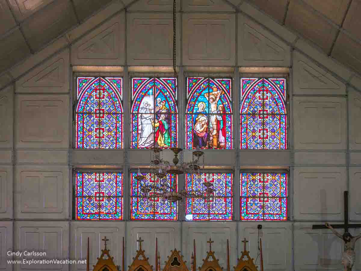 Colored glass windows that depict the magi visiting the infant Jesus and the women surrounding Jesus on the cross. 