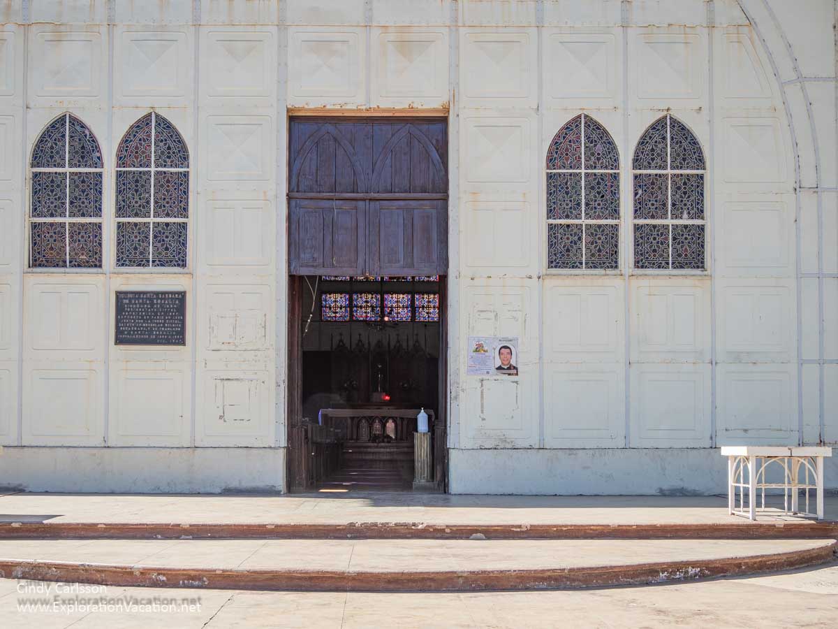 The front door and simple windows in the white metal Church of Santa Barbara.