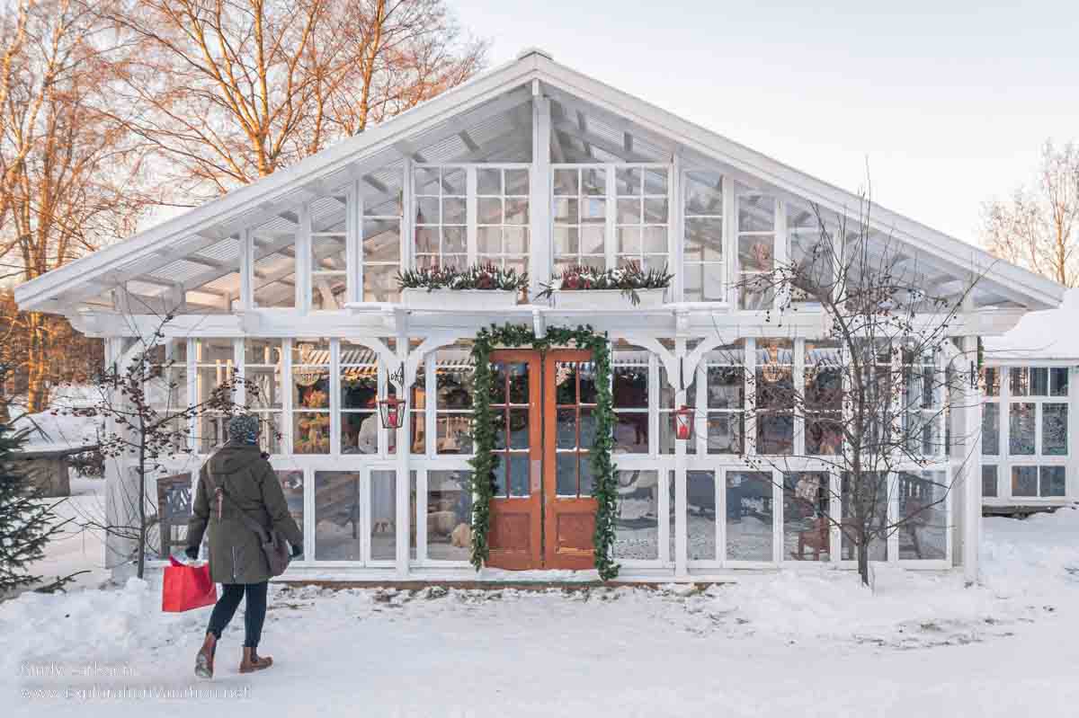 Photo of a contemporary glass building with a woman standing in front of it at the Tyynel&auml; Elf Village (Tyynel&auml;n Tonttukyl&auml;) in Larsmo, Finland. (Photos &copy; Cindy Carlsson at ExplorationVacation.net)