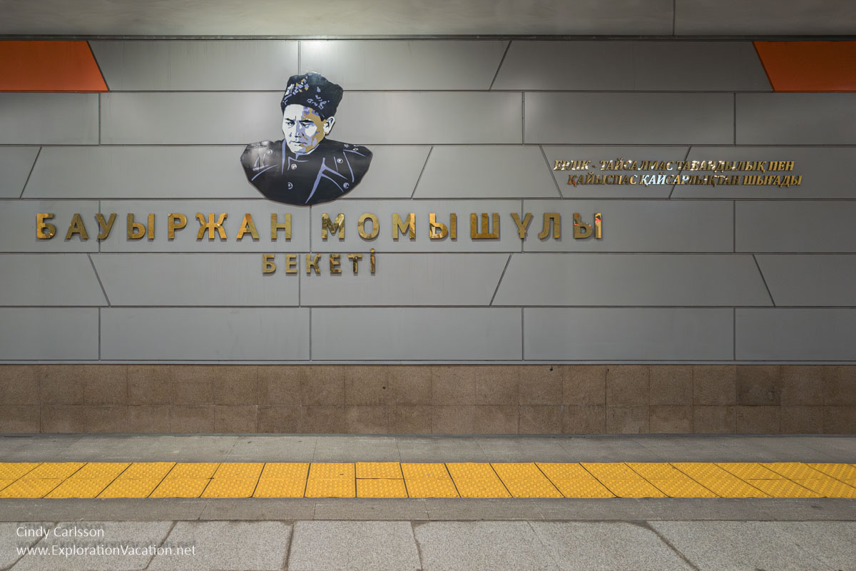 A tile wall with the figure of a man and the subway station name in the Almaty metro.