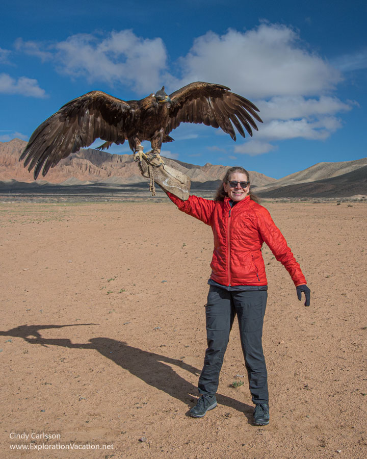 A woman holding an eagle with its wings spread above her head.