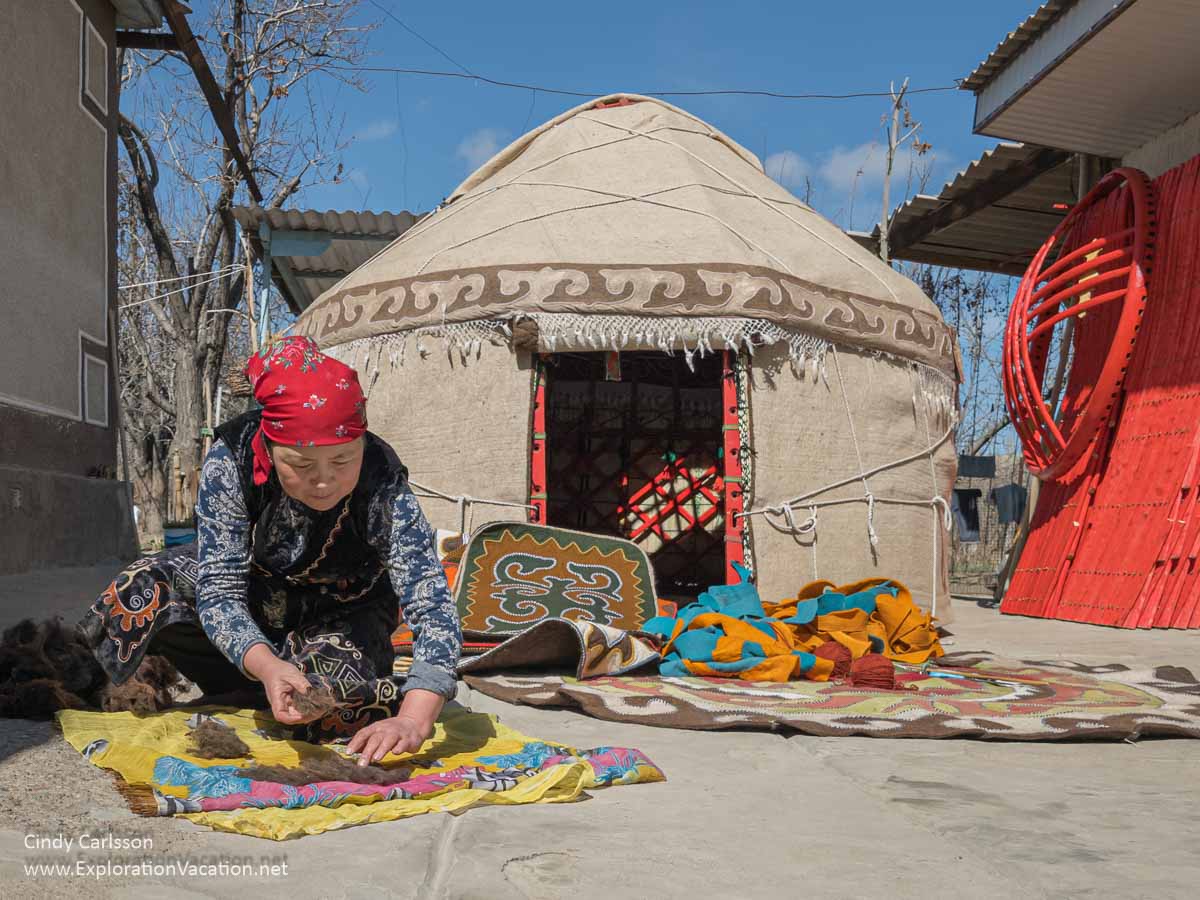 A woman felting decorative textiles in front of a traditional yurt.