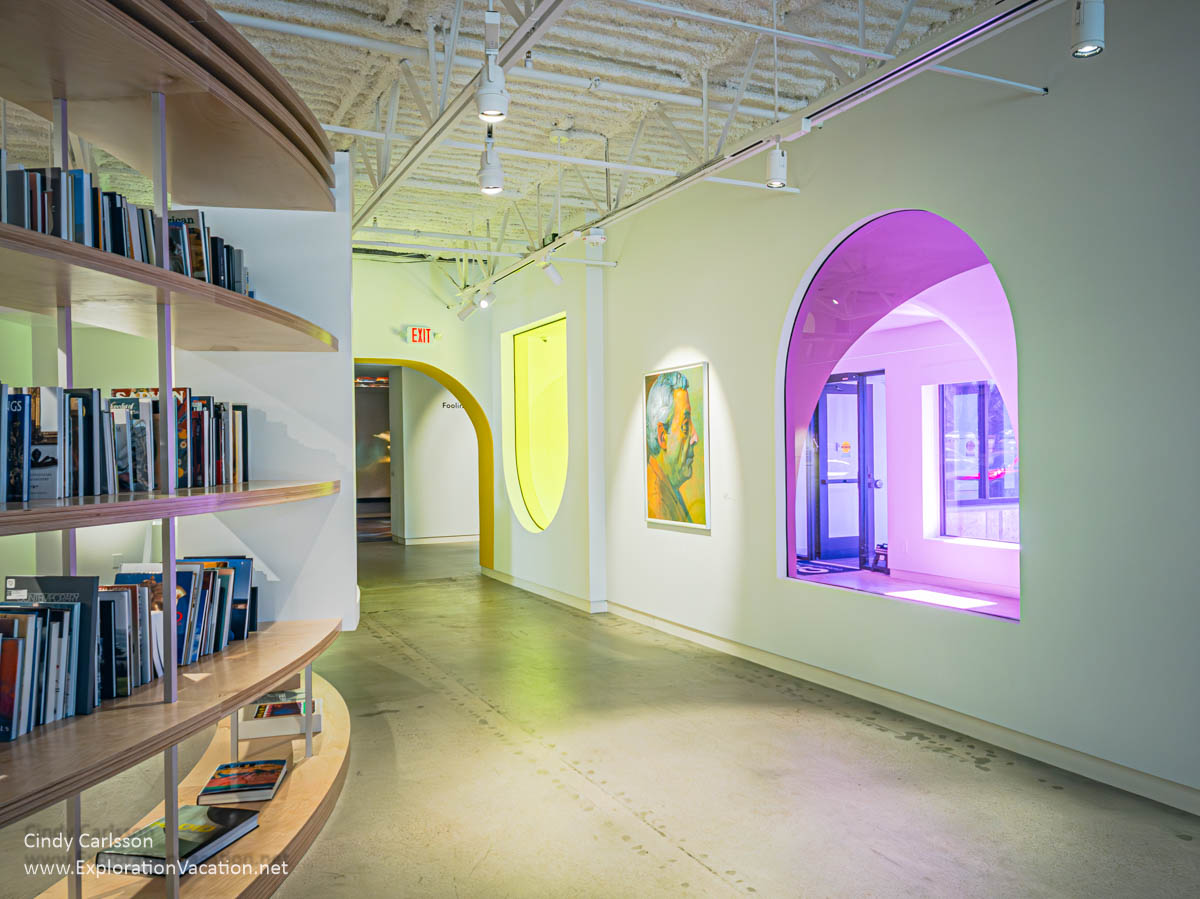 Interior of the Cafesjian Art Trust Museum, with the library on the left and the exterior door visible through a colored window to the right.