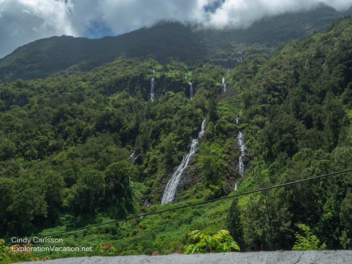 Multiple waterfalls tumbling down a forested mountainside.