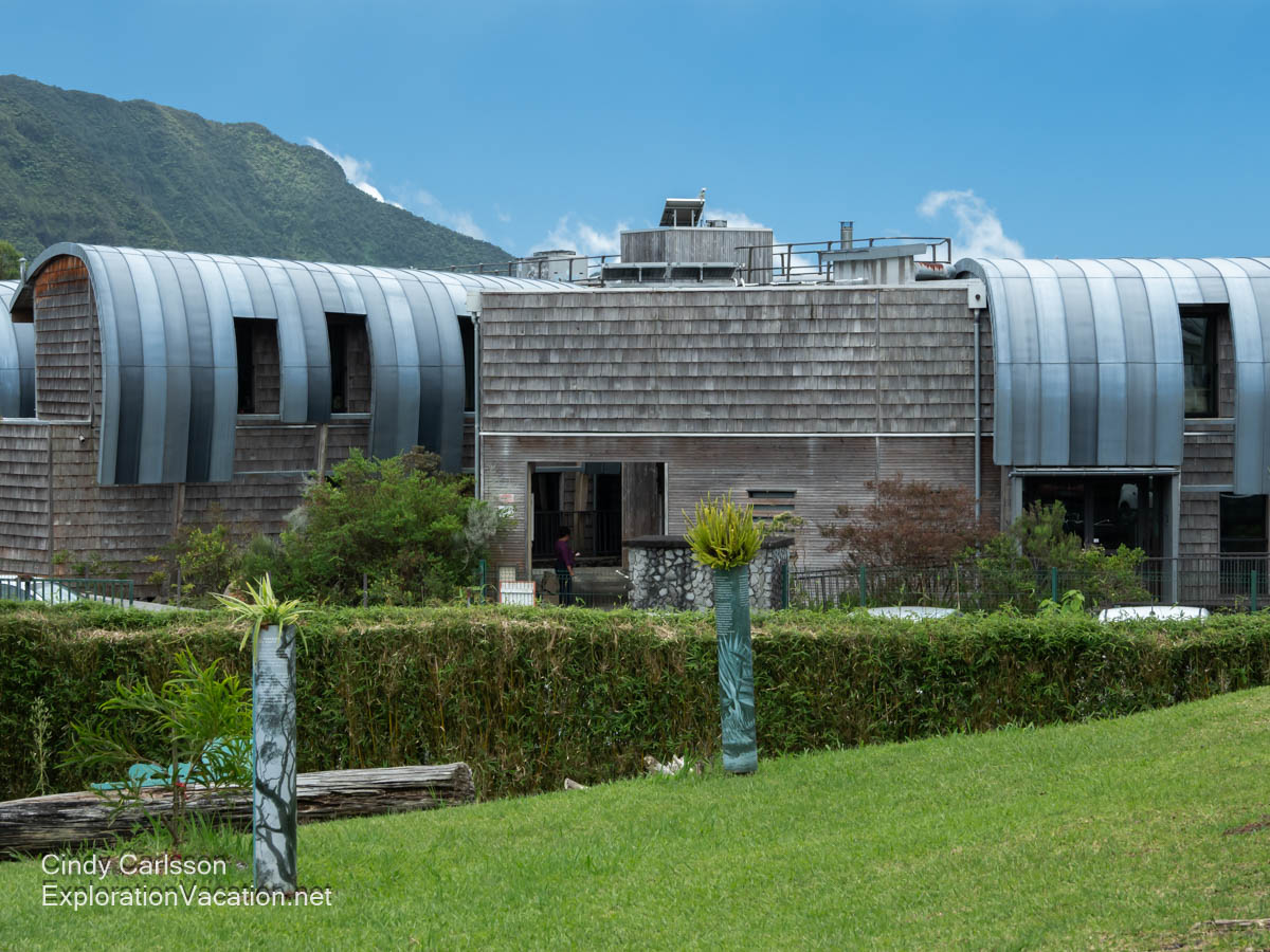 A portion of a building constructed with a mix of rounded metal panels and wooden shingles.