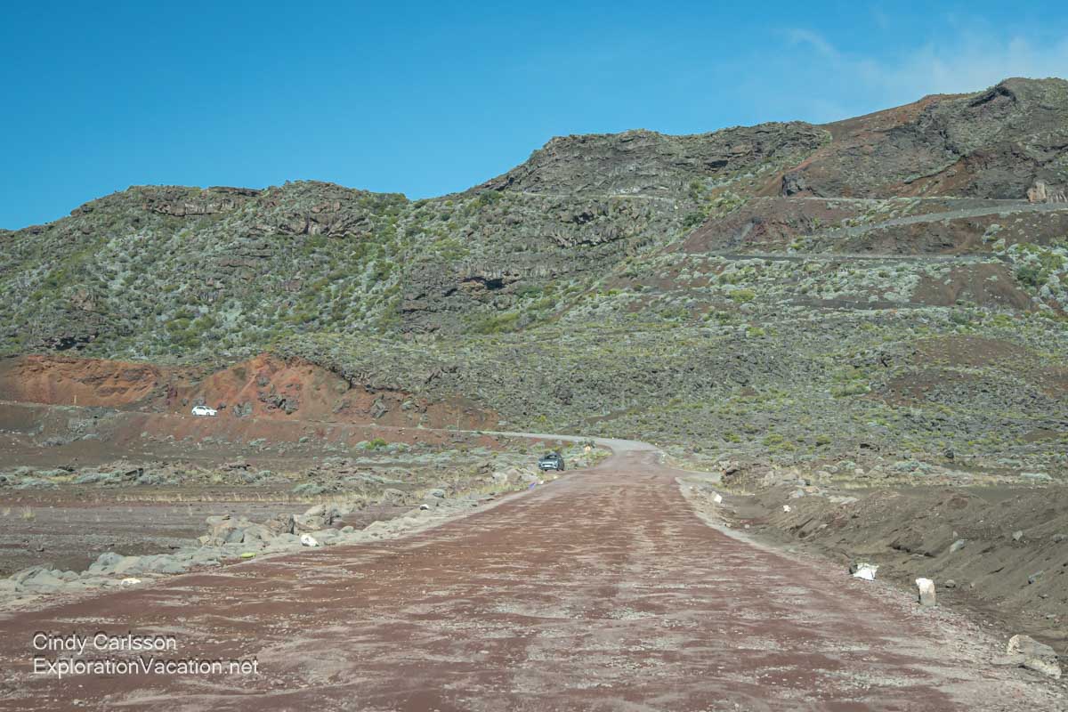 A very rutted dirt road that runs through the plain with the mountainous crater walls in the background.