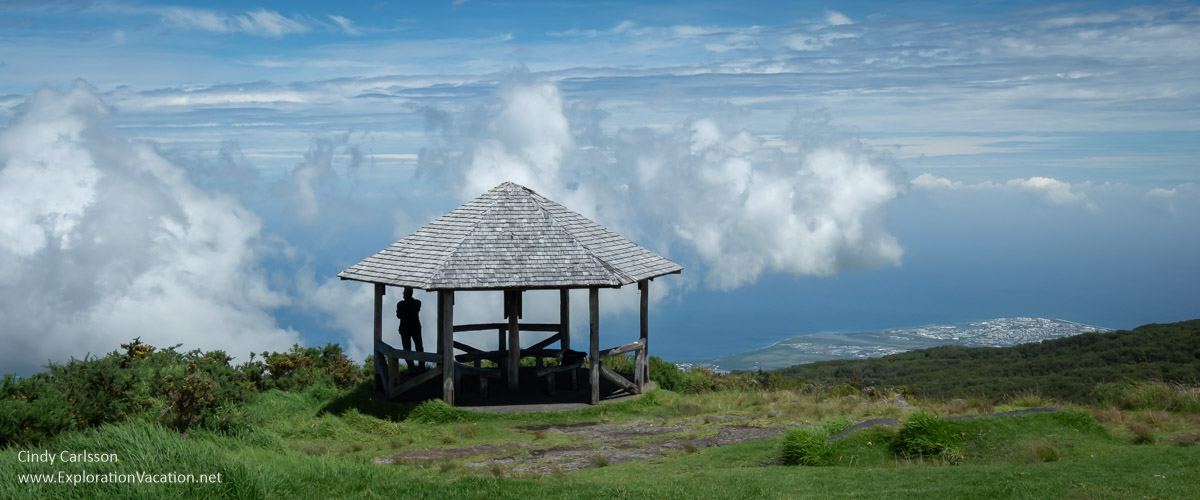 A picnic shelter with a man admiring the view of the coast far below.