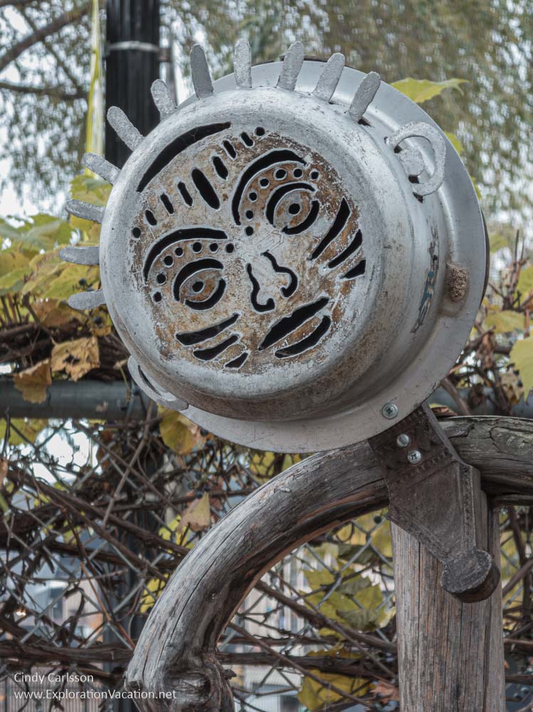A figure made out of old wood and a metal pan cut to create a human face.